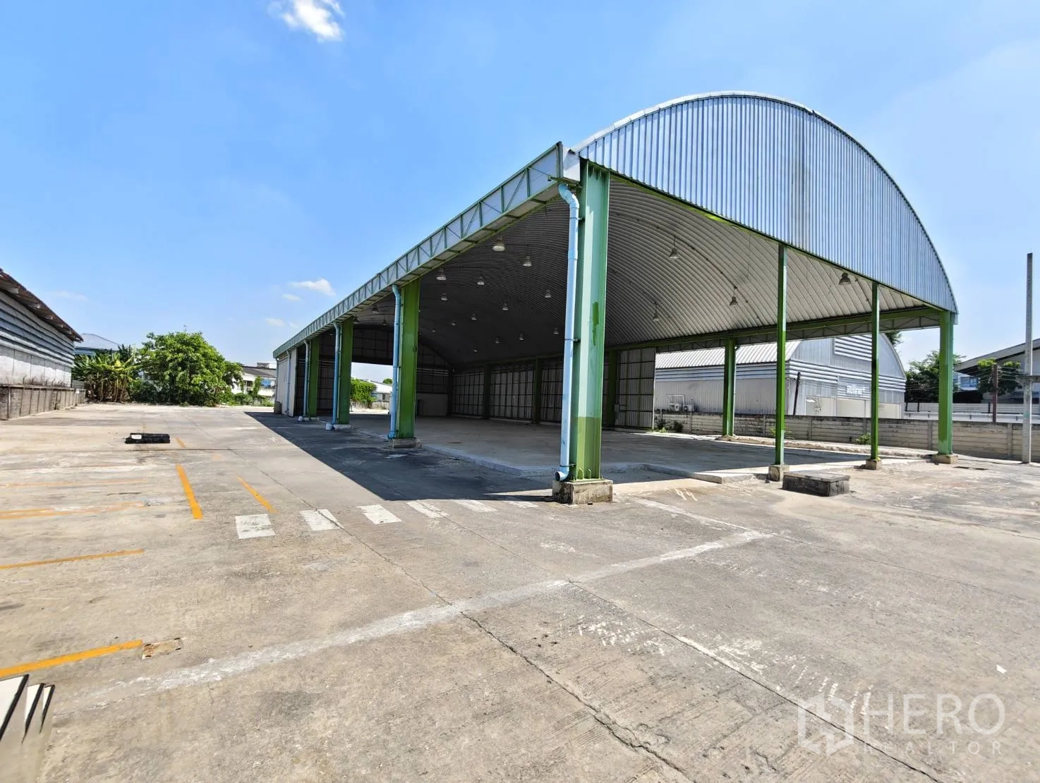 Warehouse for rent in Lak Si, Bangkok - Angled view of steel canopy warehouse showing parking markings and truck maneuvering space.