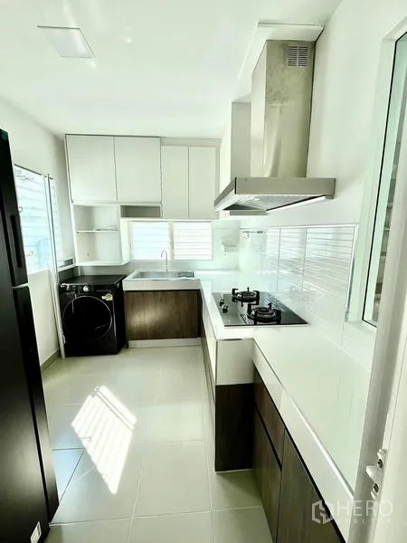Detached House for rent - Bright galley kitchen with white cabinetry, gas hob, stainless hood, windows and laundry space.