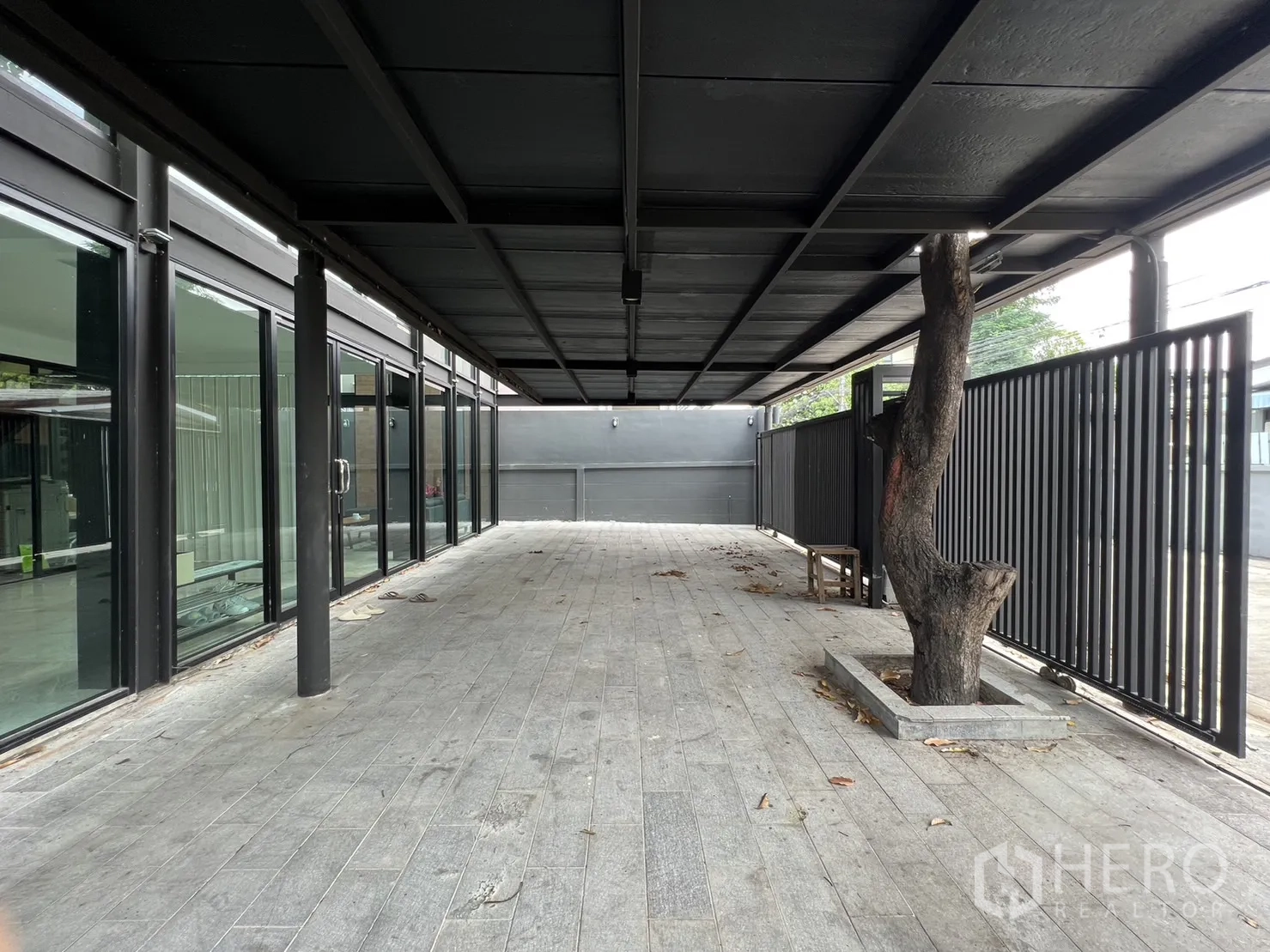 Detached House for rent or sale in Phra Khanong, Bangkok - Long covered terrace and parking area with slatted fence and integrated tree planter.