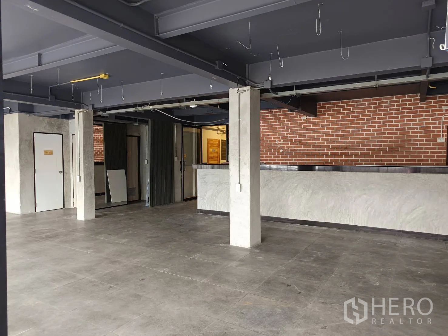 Retail Space for rent in Watthana, Bangkok - Retail floor showing service counter, multiple doors and a brick accent backdrop.
