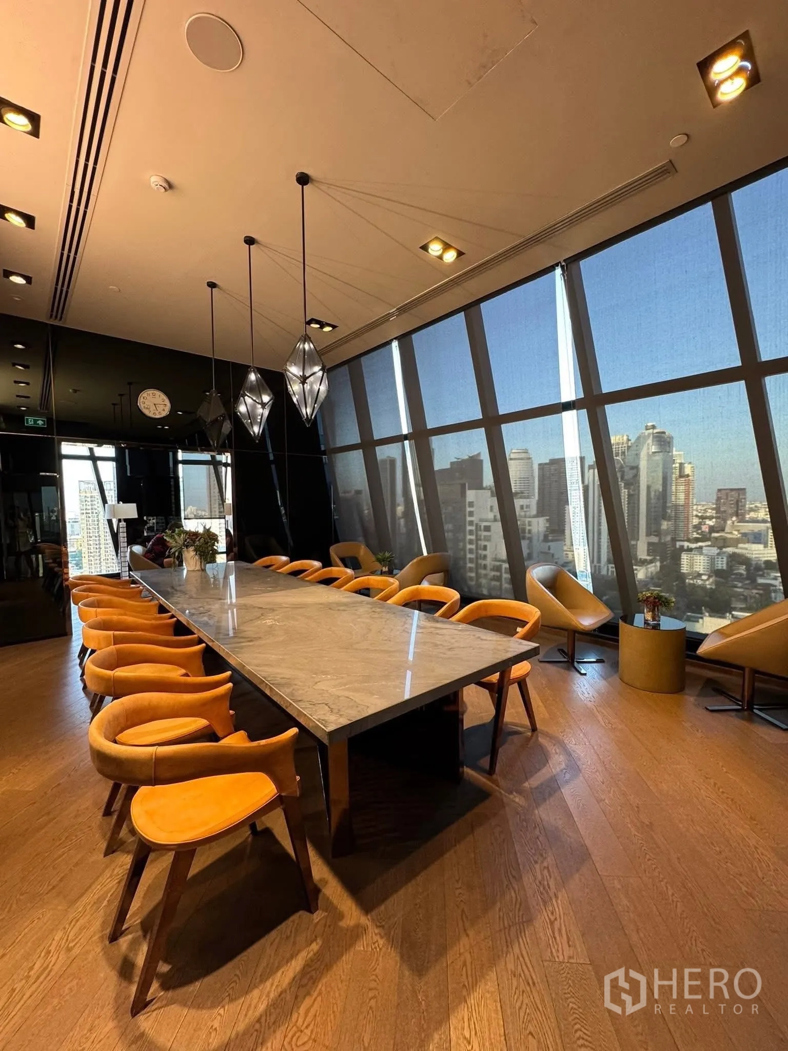Condominium for rent in Khlong Toei, Bangkok - Meeting room with a long marble table, pendant lights and skyline backdrop.