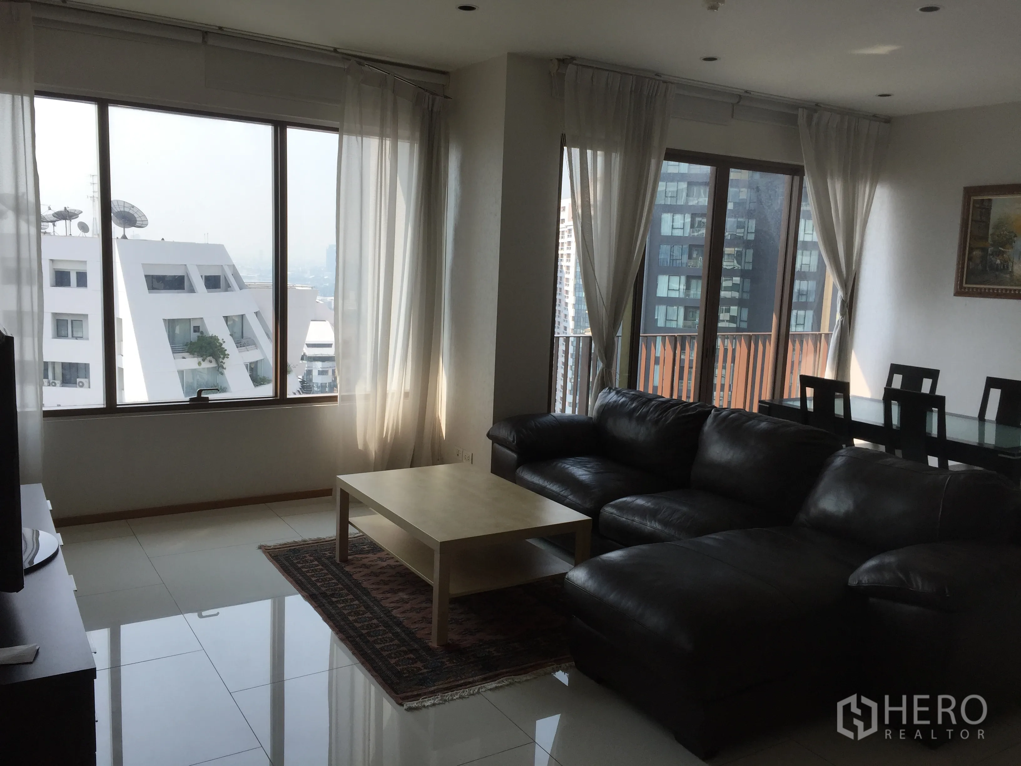 公寓 出租或出售在Khlong Toei, Bangkok - 转角客厅，透过宽窗与纱帘可见城市景观，旁接用餐区。