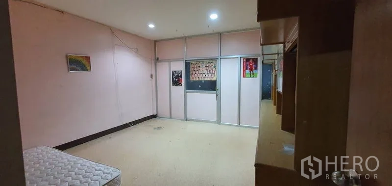 Warehouse for rent in Bang Kho Laem, Bangkok - Interior room with built-in shelving, glass partition, and pink walls.