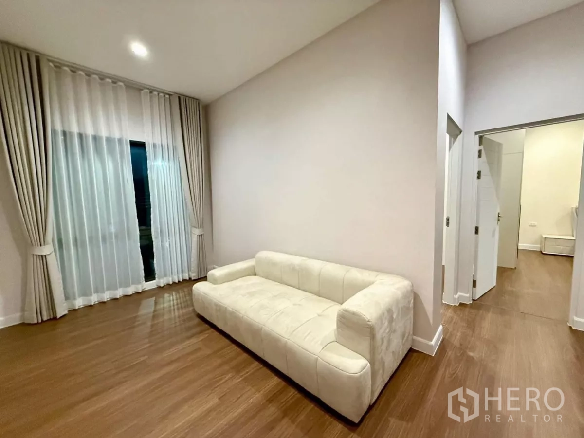 独立式住宅 出租在Bang Phli, Samut Prakan - 二层家庭起居区，奶油色沙发、木地板与纱帘。