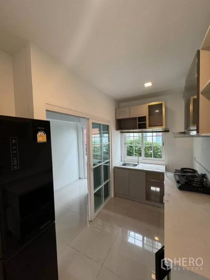 Detached House for rent in Thanyaburi, Pathum Thani - Bright kitchen with window, built-in cabinets, stovetop and refrigerator.