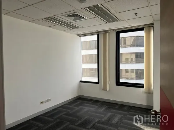 Office Space for rent in Khlong Toei, Bangkok - Private office room with two tall windows, vertical blinds and carpet flooring.