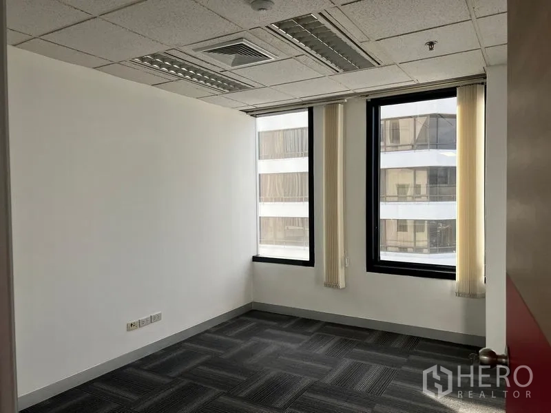 Office Space for rent in Khlong Toei, Bangkok - Private office room with two tall windows, vertical blinds and carpet flooring.