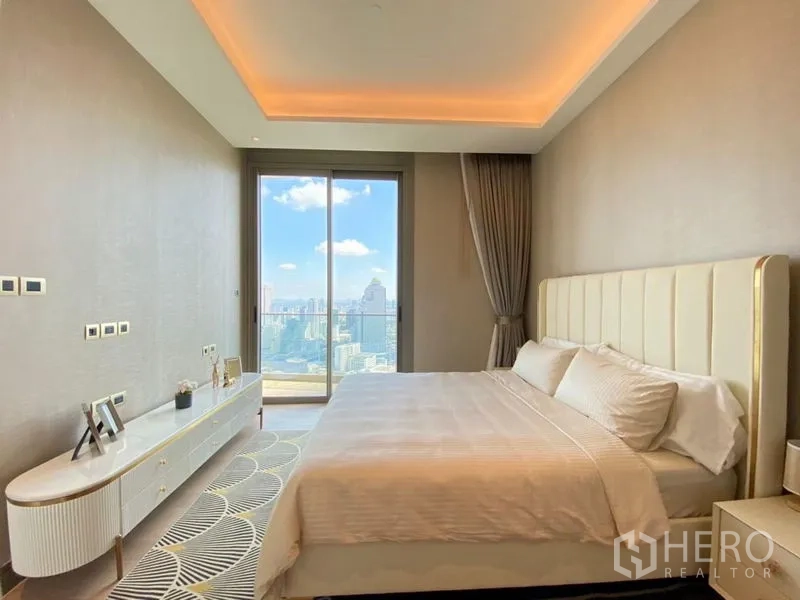 公寓 出租在Khlong San, Bangkok - 宽敞卧室，天花暗藏灯光，阳台框出城市远景。