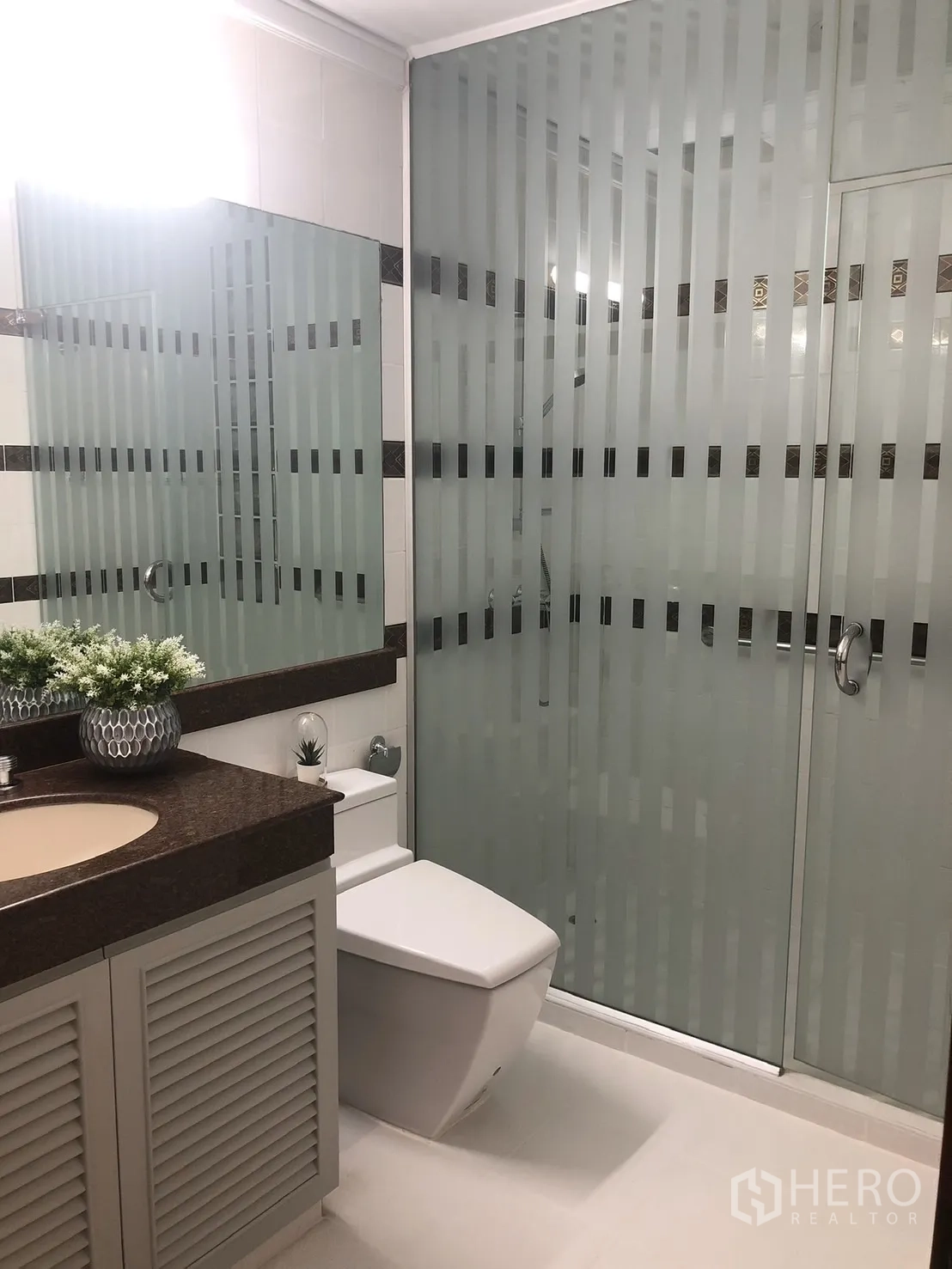 Condominium for rent in Bangkok - Contemporary bathroom with frosted glass shower and stone vanity.