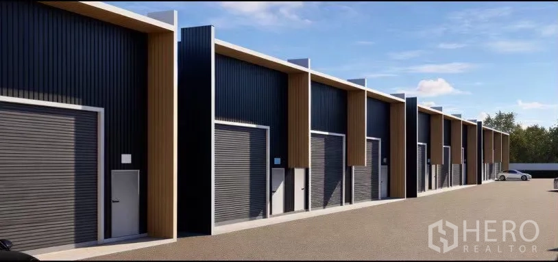 Warehouse for rent in Wang Thonglang, Bangkok - Close view of the warehouse row showing roller shutter bays and side entry doors along the drive.