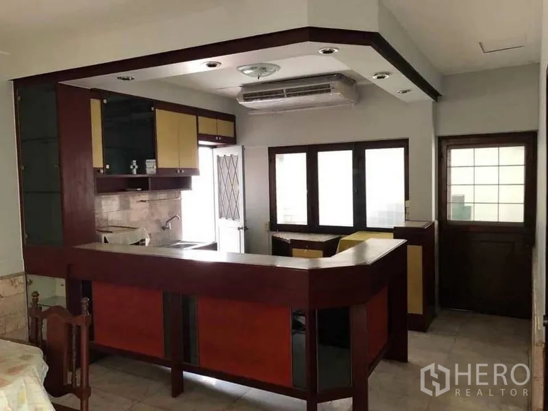 Detached House for rent in Phra Khanong, Bangkok - Closed kitchen with wood bar counter, overhead cabinets and windows.