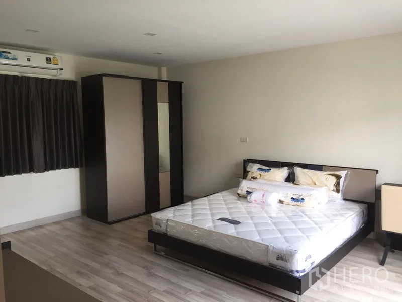 Townhouse for rent or sale in Saphan Sung, Bangkok - Spacious master bedroom with large wardrobe, wood-style flooring and air conditioner.