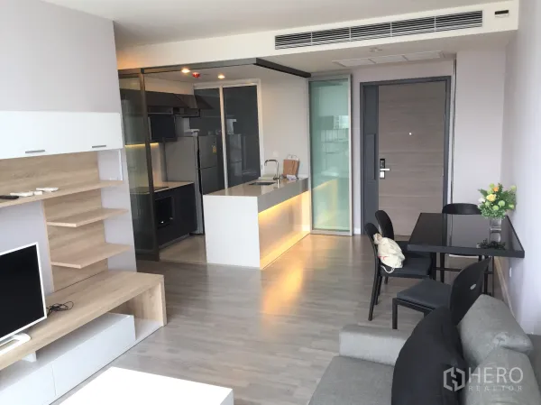 Condominium for rent in Bang Rak, Bangkok - Open-plan living and dining area with a modern kitchen island and glass partition in a 2-bedroom Bang Rak condo.