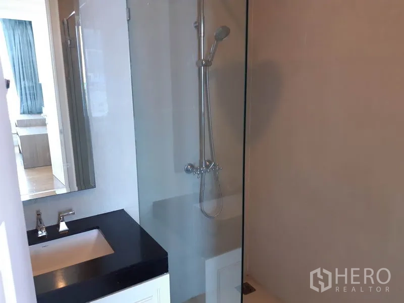 公寓 出租在Watthana, Bangkok - 浴室配玻璃淋浴间与黑色石材台面的洗手台。