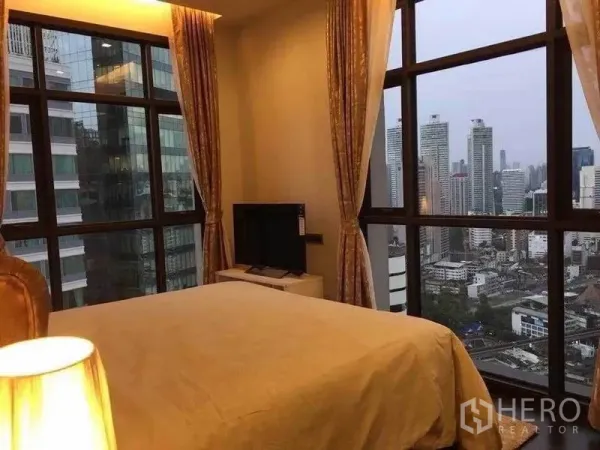Condominium for rent in Watthana, Bangkok - Bedroom with floor-to-ceiling corner windows showcasing a Bangkok skyline view.