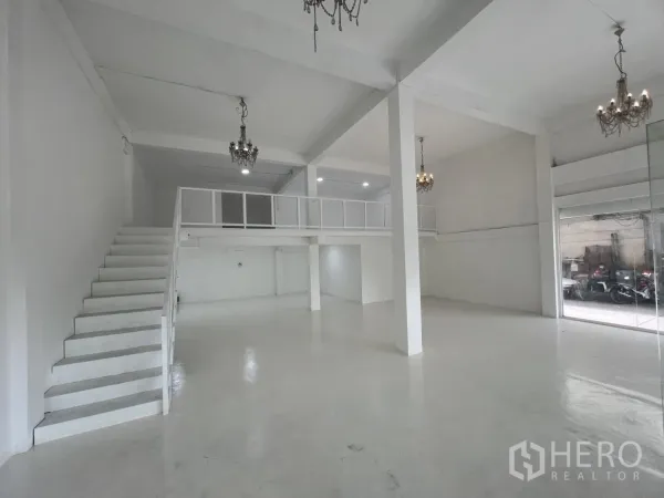 Retail Space for rent in Khlong Toei, Bangkok - Spacious retail hall with staircase to mezzanine, support columns and floor-to-ceiling windows.