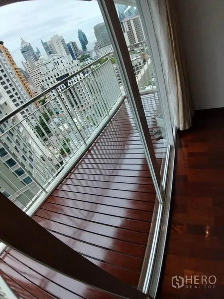Condominium for rent or sale in Pathum Wan, Bangkok - Sliding glass doors to a narrow balcony with wooden decking and wide city skyline views.