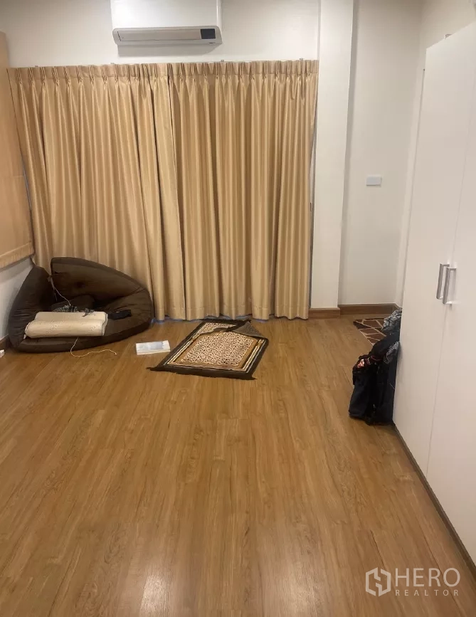 Detached House for rent or sale in Saphan Sung, Bangkok - Bedroom with wood floors, built-in storage and full-length curtains.