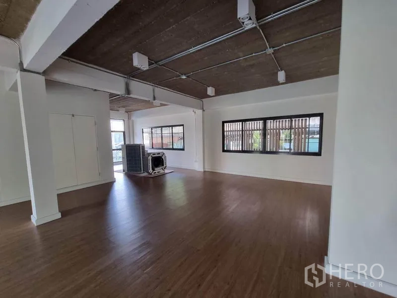 Home Office for rent or sale in Phaya Thai, Bangkok - Spacious open-plan office with wood flooring, white walls, exposed ceiling piping and wide windows.