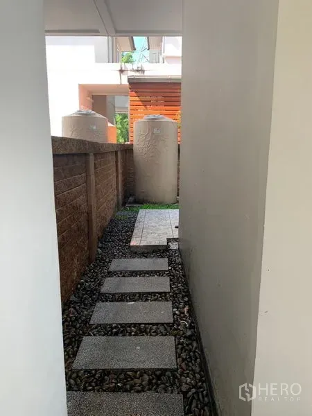 独立式住宅 出售在Prawet, Bangkok - 侧边通道，铺踏步石通向户外杂物区。