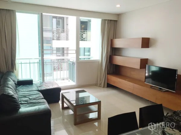 公寓 出租或出售在Watthana, Bangkok - 采光充足的客厅，连通阳台，皮沙发、电视与木质壁柜