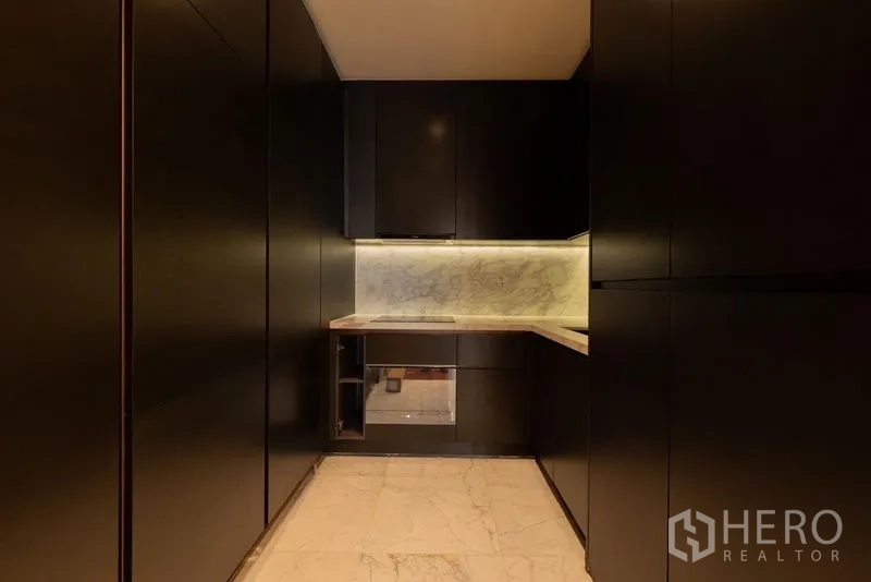 Condominium for rent in Watthana, Bangkok - Sleek dark-tone kitchen with marble countertop and backsplash.