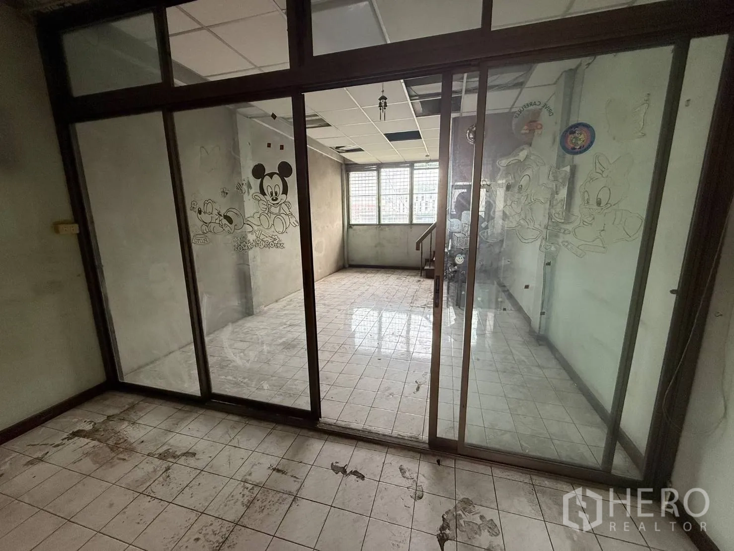 Shophouse for rent in Khlong Toei, Bangkok - View through sliding glass doors into a light-filled tiled room.