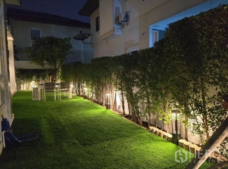 Detached House for rent - Side yard at night with trimmed hedges, path lighting and outdoor dining set.
