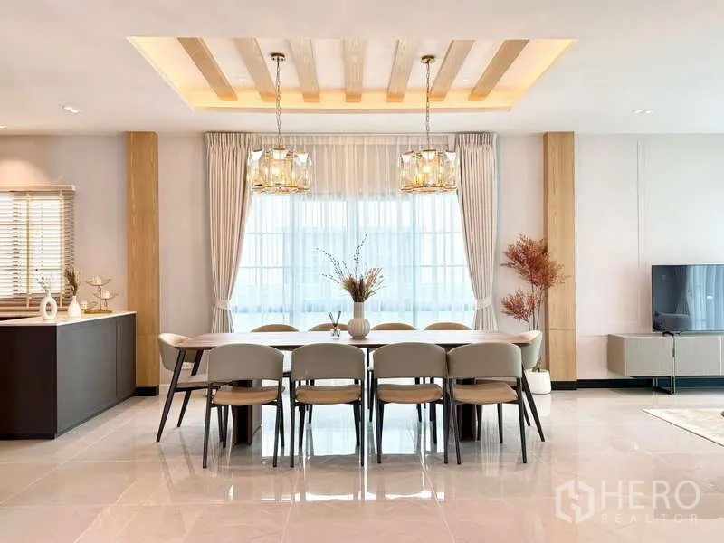 Detached House for rent or sale in Bang Phli, Samut Prakan - Open-plan dining room with a long table for ten, chandelier lighting and large windows.