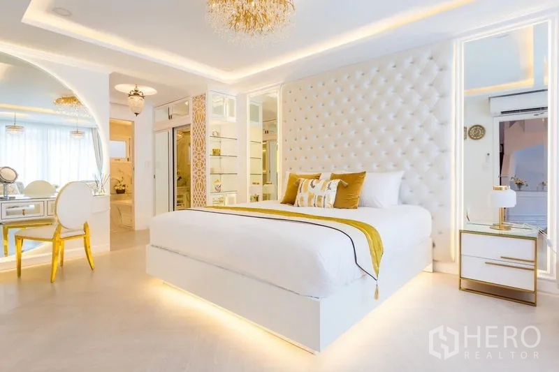 Townhouse for rent in Lat Phrao, Bangkok - Spacious master bedroom with tufted headboard, under-bed lighting, vanity area and modern ceiling details.