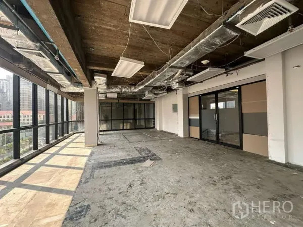 Office Space for rent - Unfurnished office floor featuring a glass-partition meeting room and large windows bringing in natural light.
