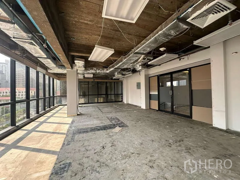 Office Space for rent - Unfurnished office floor featuring a glass-partition meeting room and large windows bringing in natural light.