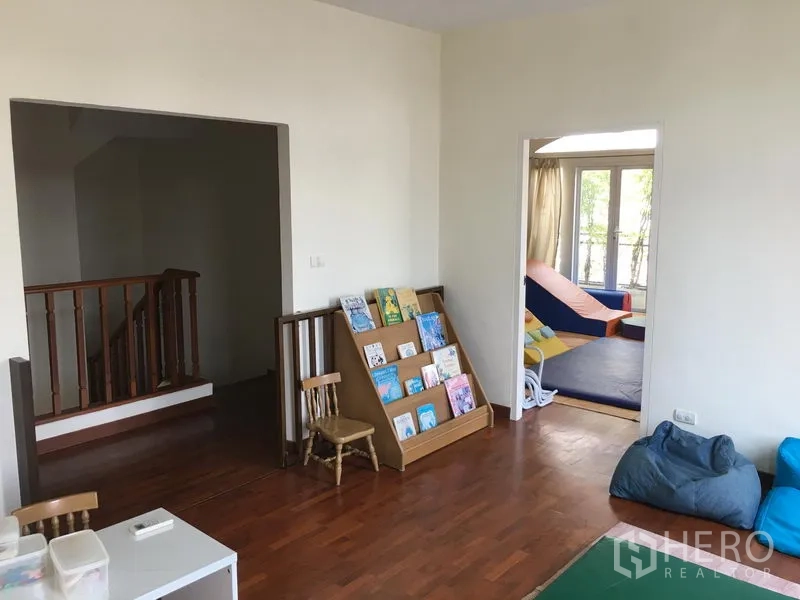 联排别墅 出售在Huai Khwang, Bangkok - 家庭房配木地板、书架，旁连带阳台卧室。