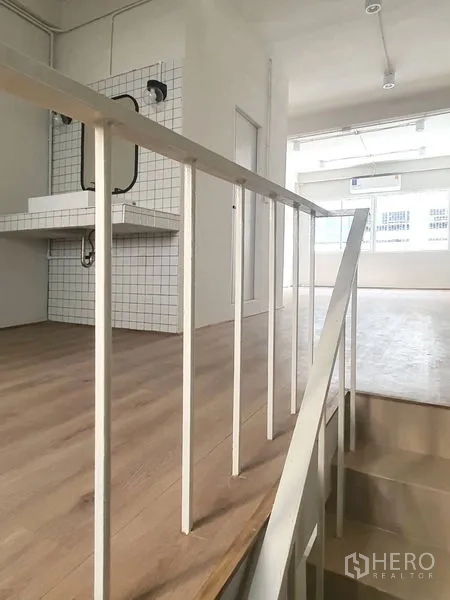 Shophouse for rent in Phra Khanong, Bangkok - Stair landing with white railing, wood flooring and a tiled wash counter with mirror.
