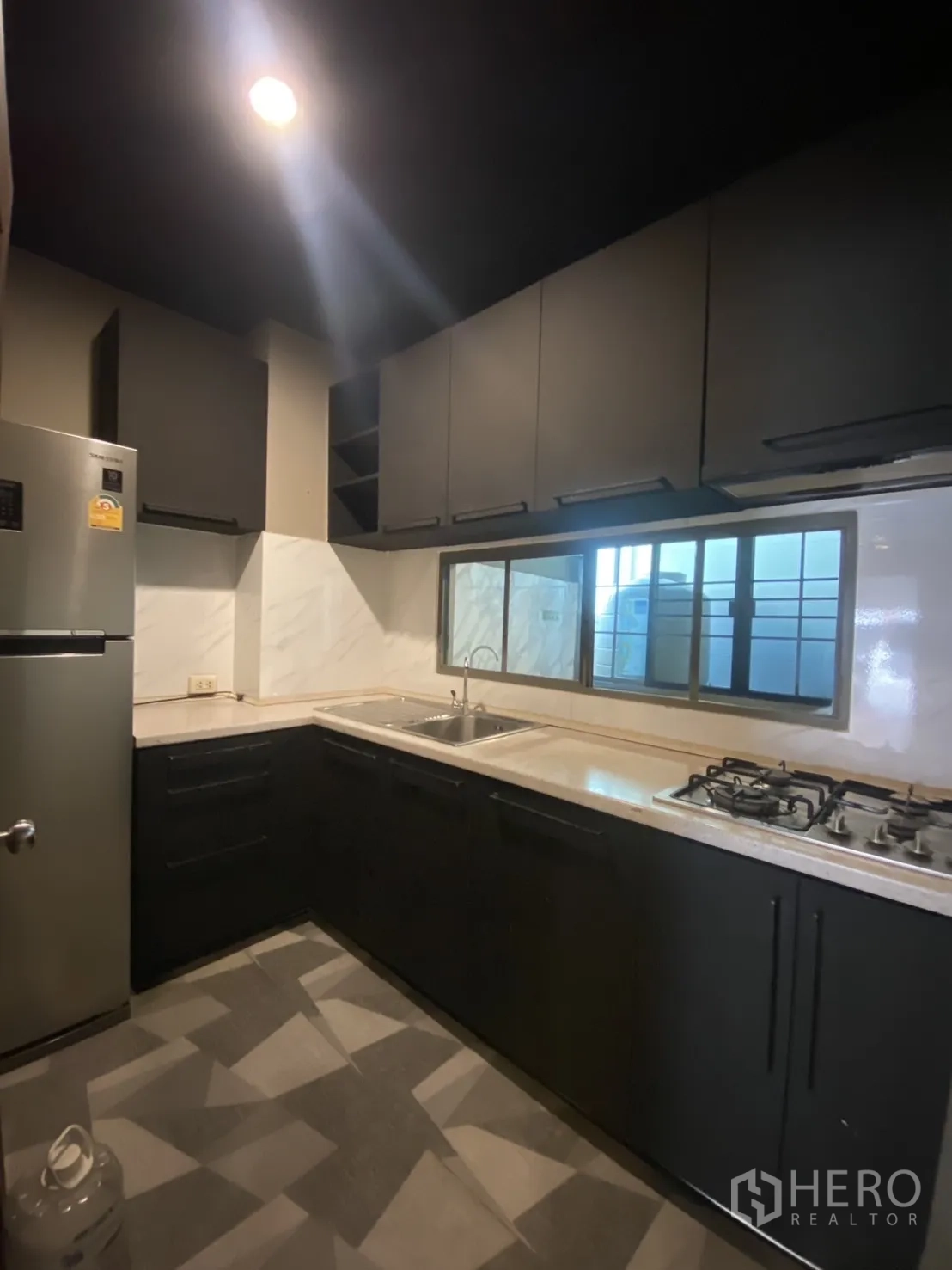 Townhouse for rent in Bang Kapi, Bangkok - L-shaped kitchen with matte cabinetry, gas cooktop and stainless sink.