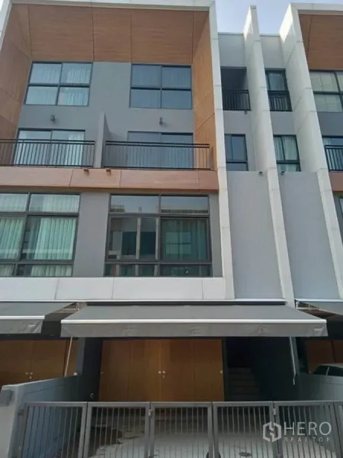 Townhouse for rent or sale in Suan Luang, Bangkok - Contemporary three-storey townhouse facade with balconies, large windows and a covered carport in Suan Luang, Bangkok.