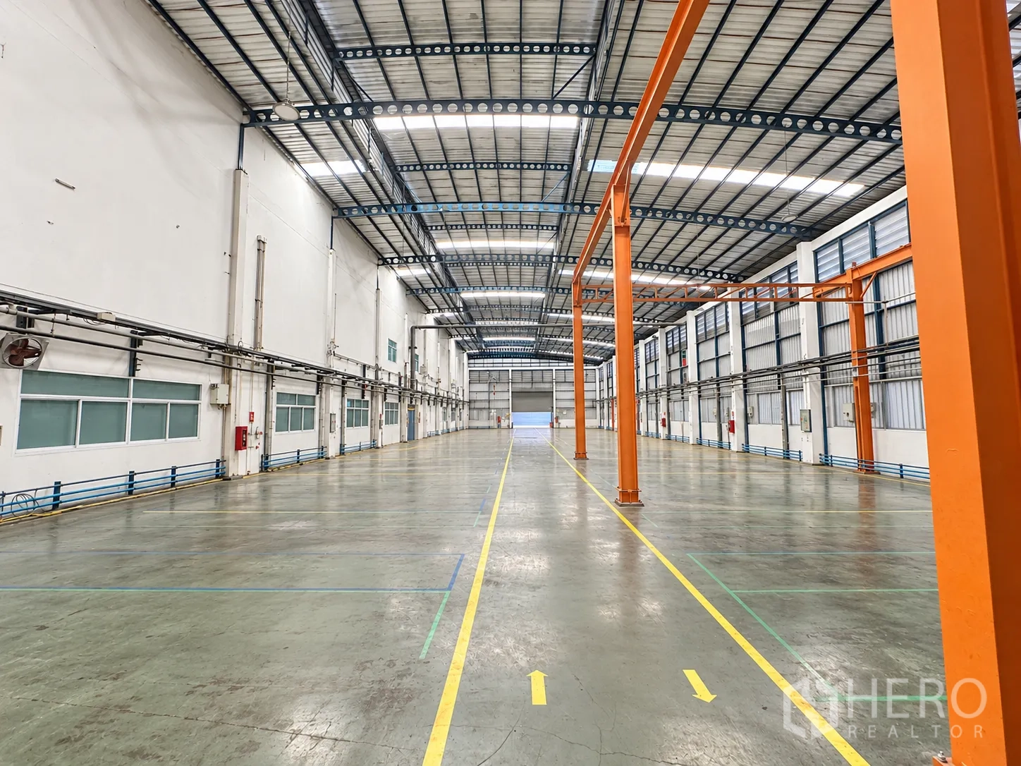 Factory for sale in Lam Luk Ka, Pathum Thani - Polished epoxy floor with lane markings beside windows and wall-mounted fans.