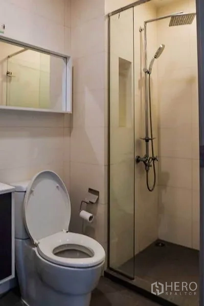 Condominium for rent in Khlong Toei, Bangkok - Bathroom with glass-enclosed rain shower, toilet and vanity.