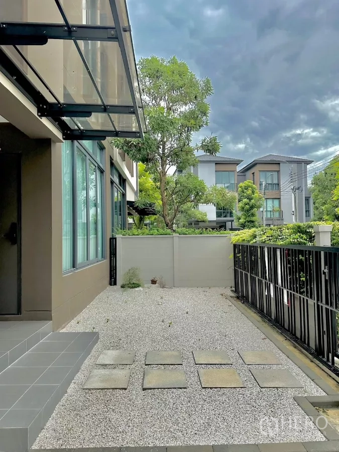 独立式住宅 出租或出售在Prawet, Bangkok - 前院碎石庭院，玻璃遮雨棚与栅栏门，临园景街道。