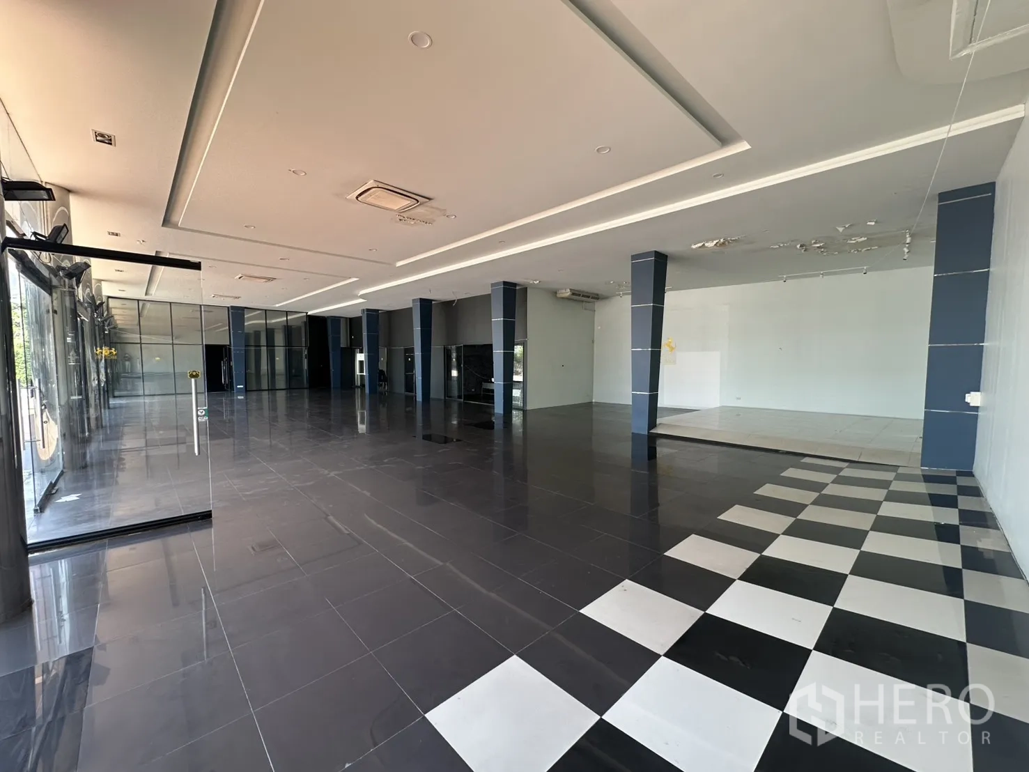Showroom for rent in Suan Luang, Bangkok - Wide shot of the sales hall showing checkerboard tiles and display stage.