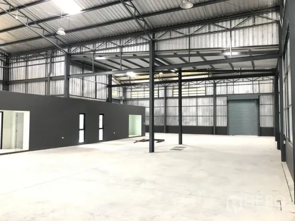 Factory for rent in Bang Yai, Nonthaburi - Spacious warehouse interior with high steel trusses, polished concrete floor and an internal office block.