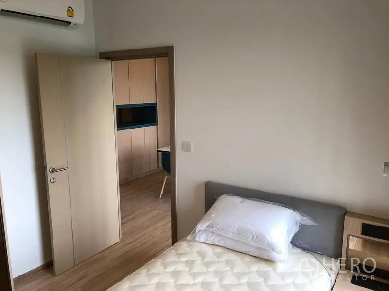 Condominium for rent in Watthana, Bangkok - Bedroom view toward hallway and kitchen cabinetry from the bed.