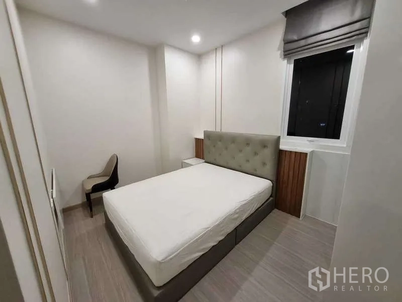 Condominium for rent - Second bedroom with tufted headboard, window and study chair.