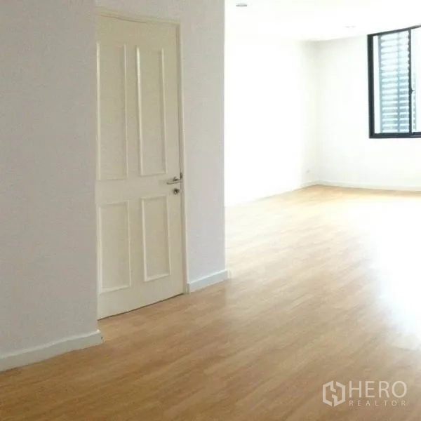 Townhouse for rent in Yan Nawa, Bangkok - Another angle of the bright wood-floored room with white door and window.
