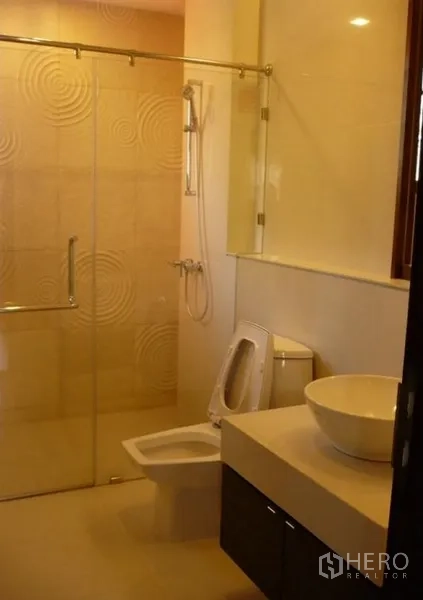 Detached House for rent in Khlong Toei, Bangkok - Modern bathroom with glass-enclosed shower, vessel sink and neutral tiles.