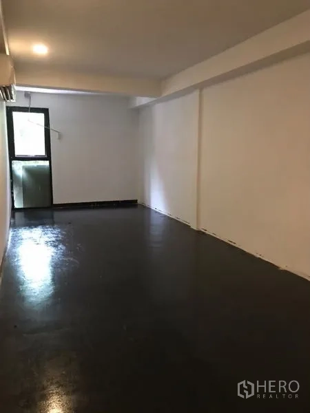 Home Office for rent or sale in Khlong Toei, Bangkok - Narrow room with black floor and a balcony door bringing in natural light.