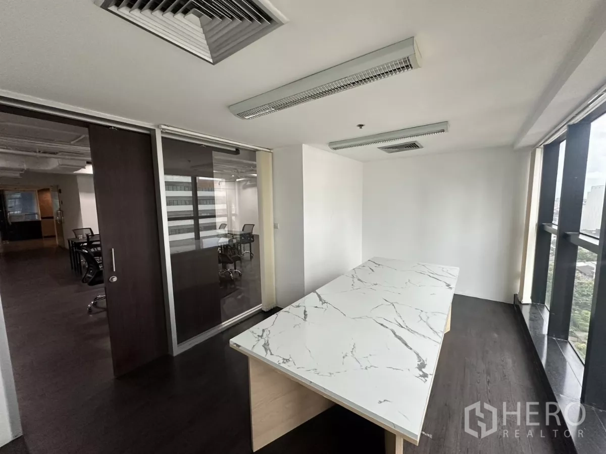 Office Space for rent in Watthana, Bangkok - Executive room with sliding glass wall and marble table facing the main work area.