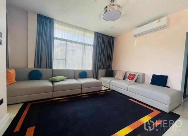Detached House for sale in Sai Mai, Bangkok - Bright living room featuring large sectional sofas, sheer curtains, and air-conditioning.