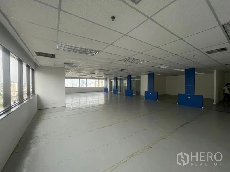 办公空间 出租 - 宽敞的办公楼层，环景窗与蓝色立柱设计。