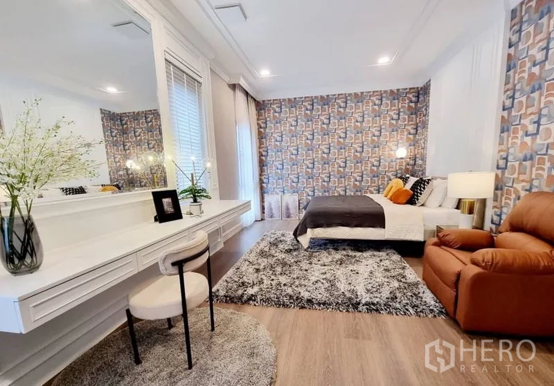 Detached House for rent in Saphan Sung, Bangkok - Spacious bedroom with long vanity desk, patterned wallpaper, and recliner chair.